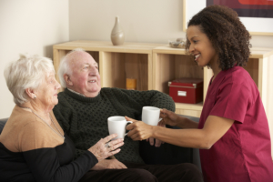 caregiver serving a drink for elderly couple